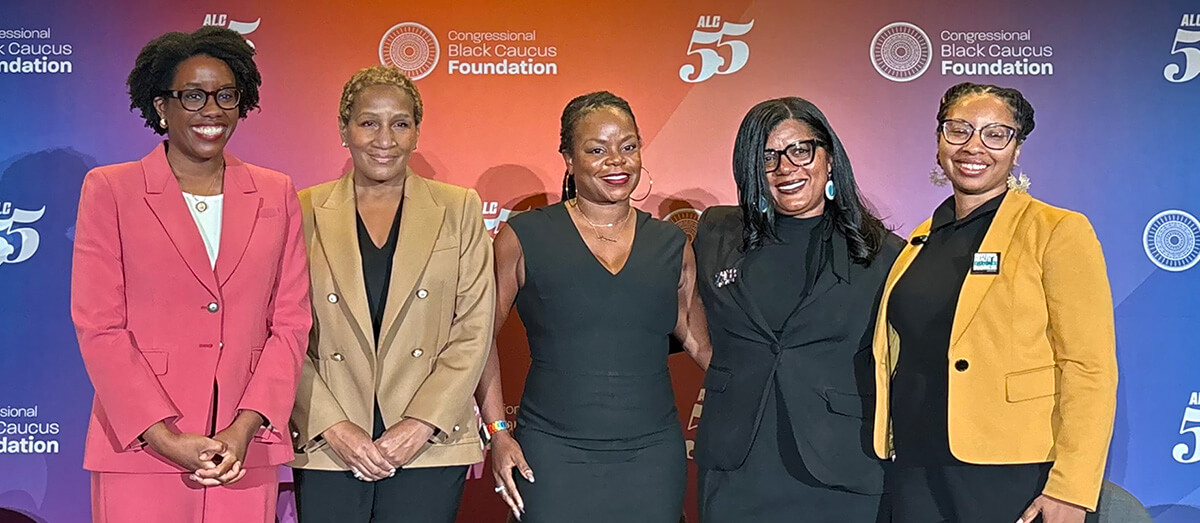 The panelists at ALC55 in front of a colorful backdrop